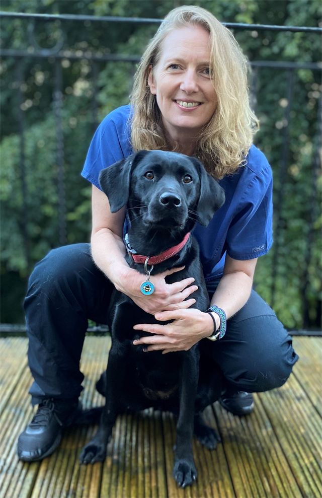 Daisy Newey crouching with Puffin, her black Labrador